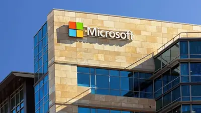 En byggnad med Microsofts logotyp och namn på fasaden. Blå himmel i bakgrunden.