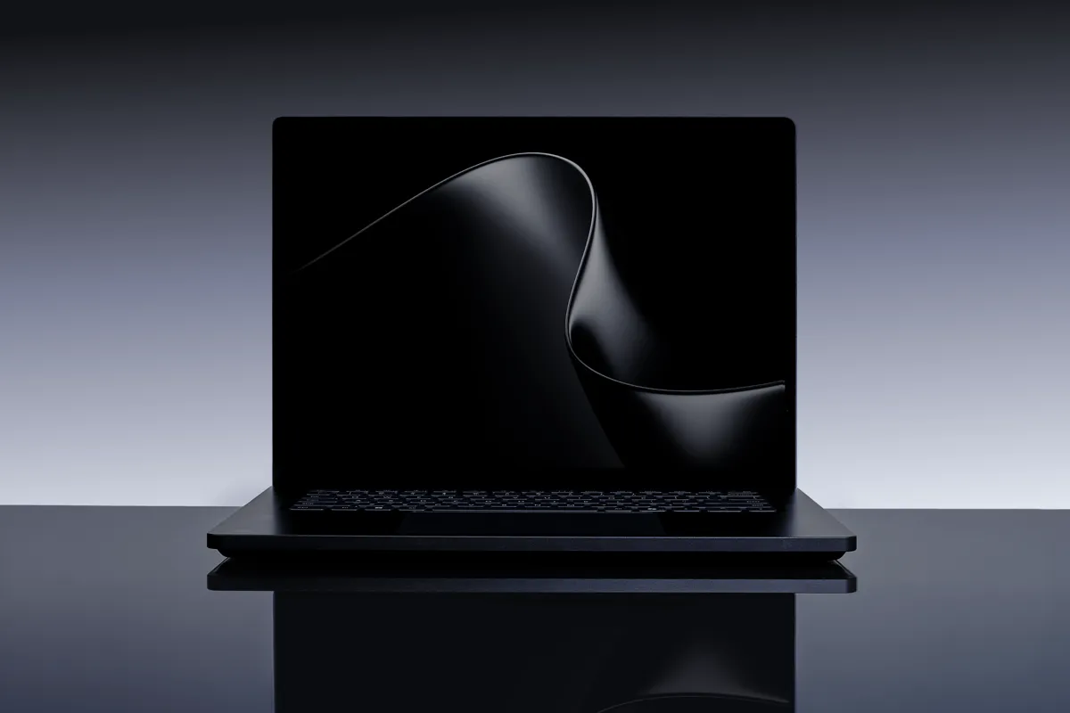 En svart Surface Laptop Ultra står på ett blankt underlag med en abstrakt svart bakgrundsbild.
