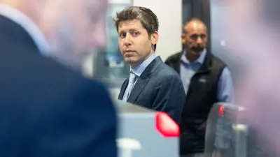 En man i kostym tittar mot kameran. En annan man i bakgrunden. Oskärpa i förgrunden.