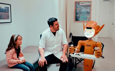 En läkare, en flicka och en orange robot med ett bricka i ett undersökningsrum.
