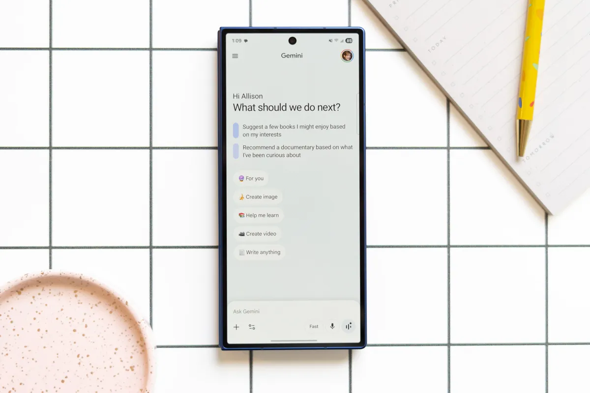 En mobiltelefon visar Googles AI Gemini med förslag på vad användaren kan göra. En anteckningsbok och penna syns bredvid.