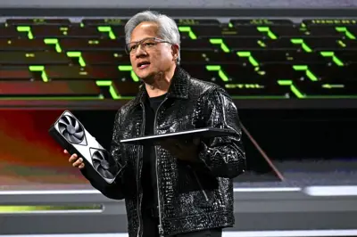 Jensen Huang, Nvidias VD, håller i ett grafikkort och en laptop på en scen.