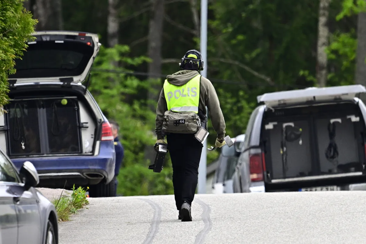En polis i gul väst går mot två bilar med öppna bakluckor.