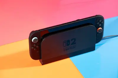 En svart Nintendo Switch 2 i dockningsstation mot en färgglad bakgrund.