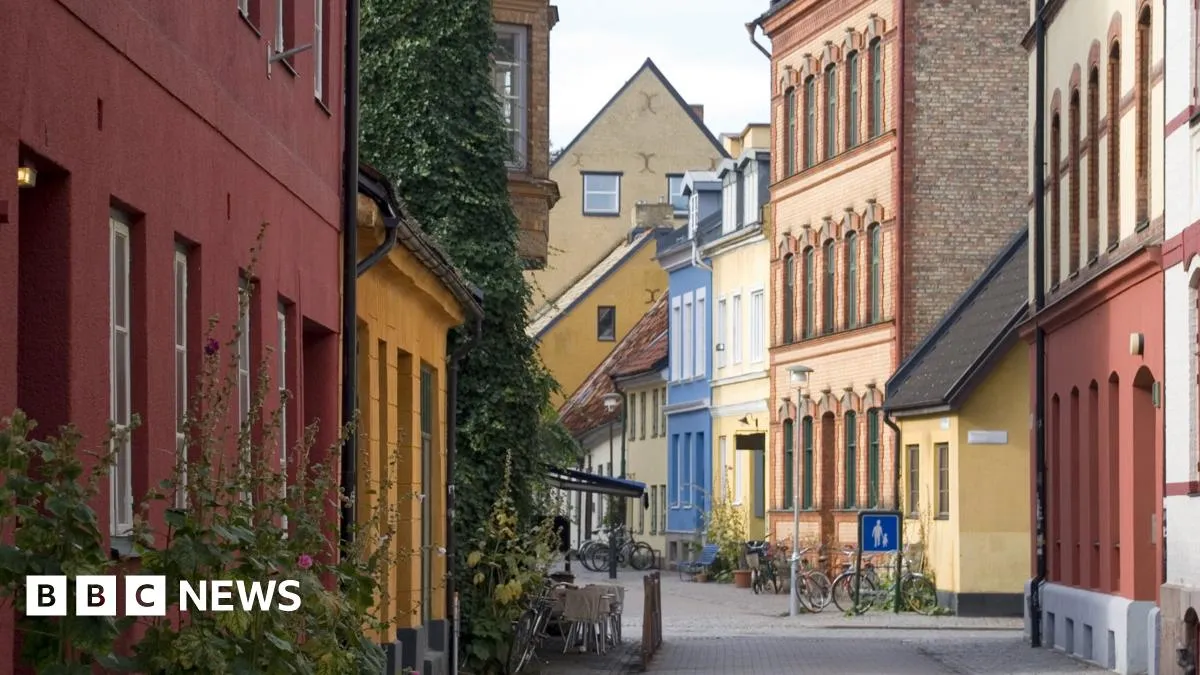 En gata med färgglada hus i olika stilar. Cyklar och en skylt syns.