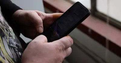 En person håller en mobiltelefon och skriver på skärmen.